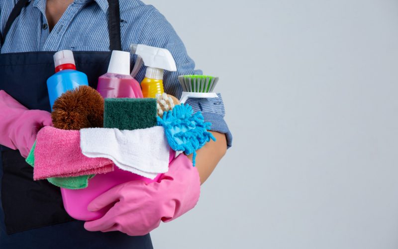 young-girl-is-holding-cleaning-product-gloves-and-rags-in-the-basin-on-white-wall
